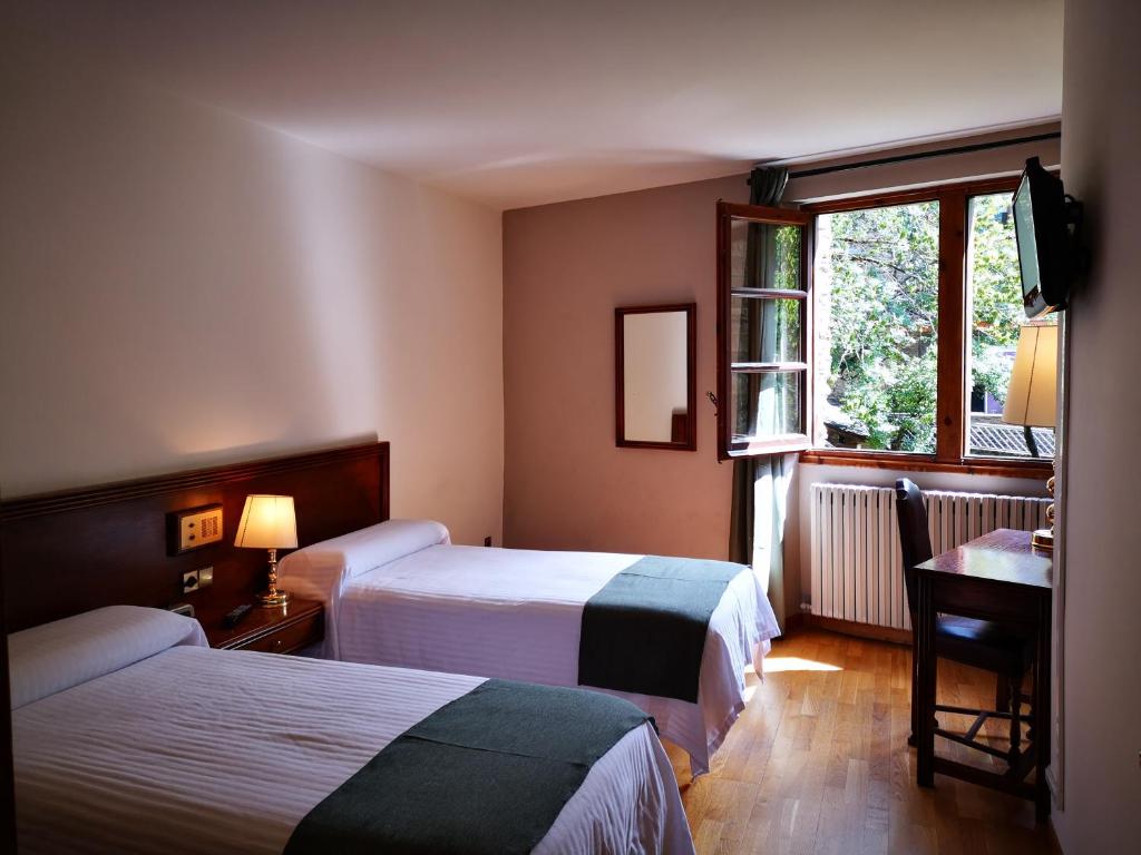 a hotel room with two beds and a window at Hotel Santa Bàrbara De La Vall D'ordino in Ordino
