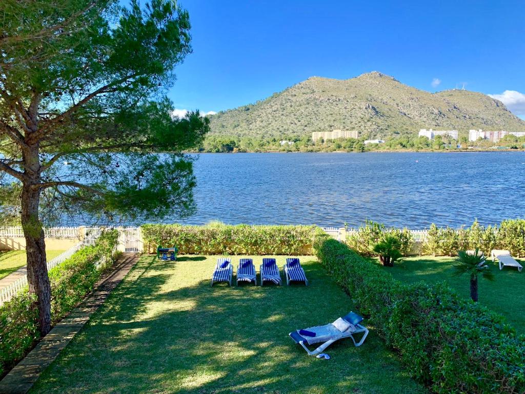 2 sillas de jardín y 2 tumbonas junto a un lago en Chalet Lago Grande, en Puerto de Alcudia