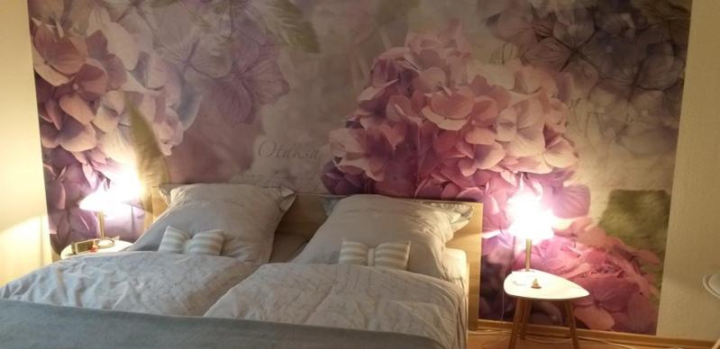 1 dormitorio con una pared de flores, 1 cama y 2 lámparas en Wohnung im Dreistädteeck en Núremberg