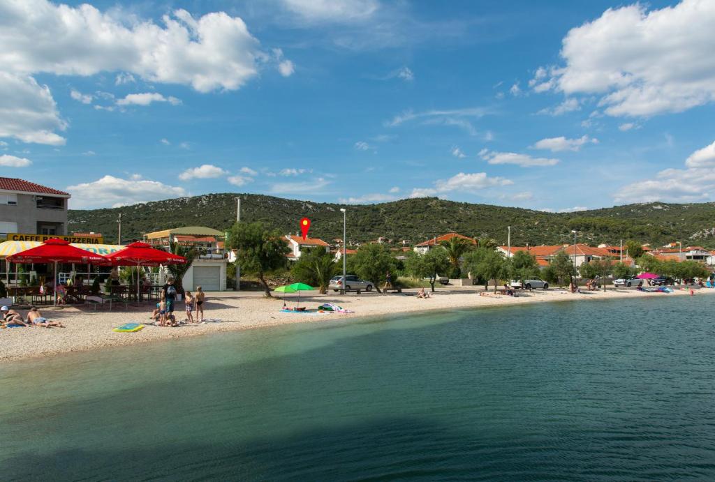 a beach with people laying on the sand and the water at Apartmani Stjepan in Vinišće