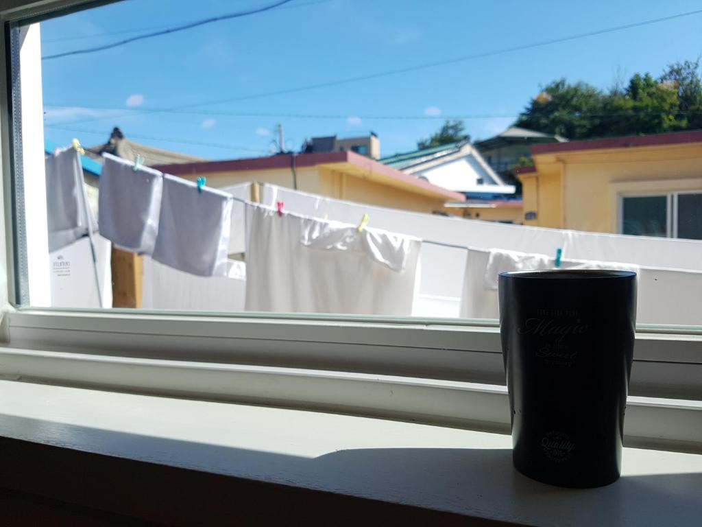 a candle sitting on a window sill next to a window with towels at Sokcho Hutte in Sokcho