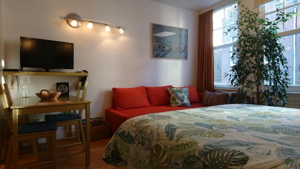 a bedroom with a bed and a red couch at Huis Roomolen in Amsterdam