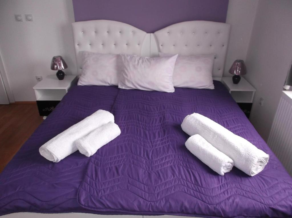 Una cama morada con dos toallas blancas. en Prenociste Bojan 017, en Vranje