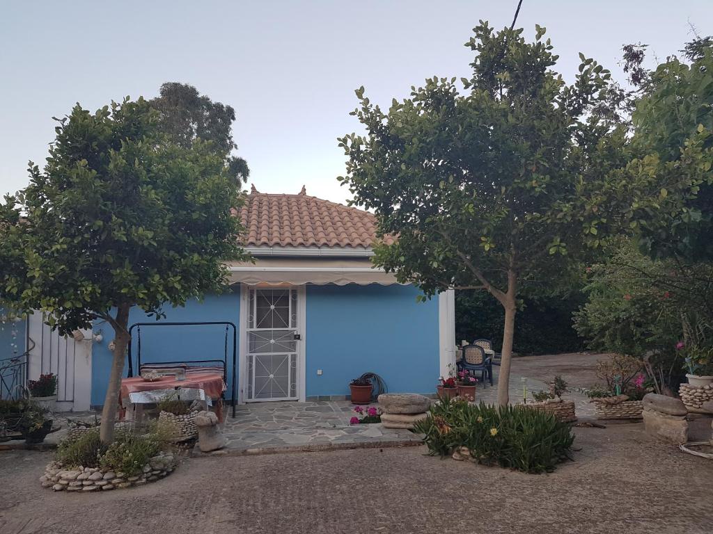 a house with a blue garage with trees at Kallithea Holiday Homes II in Alykes