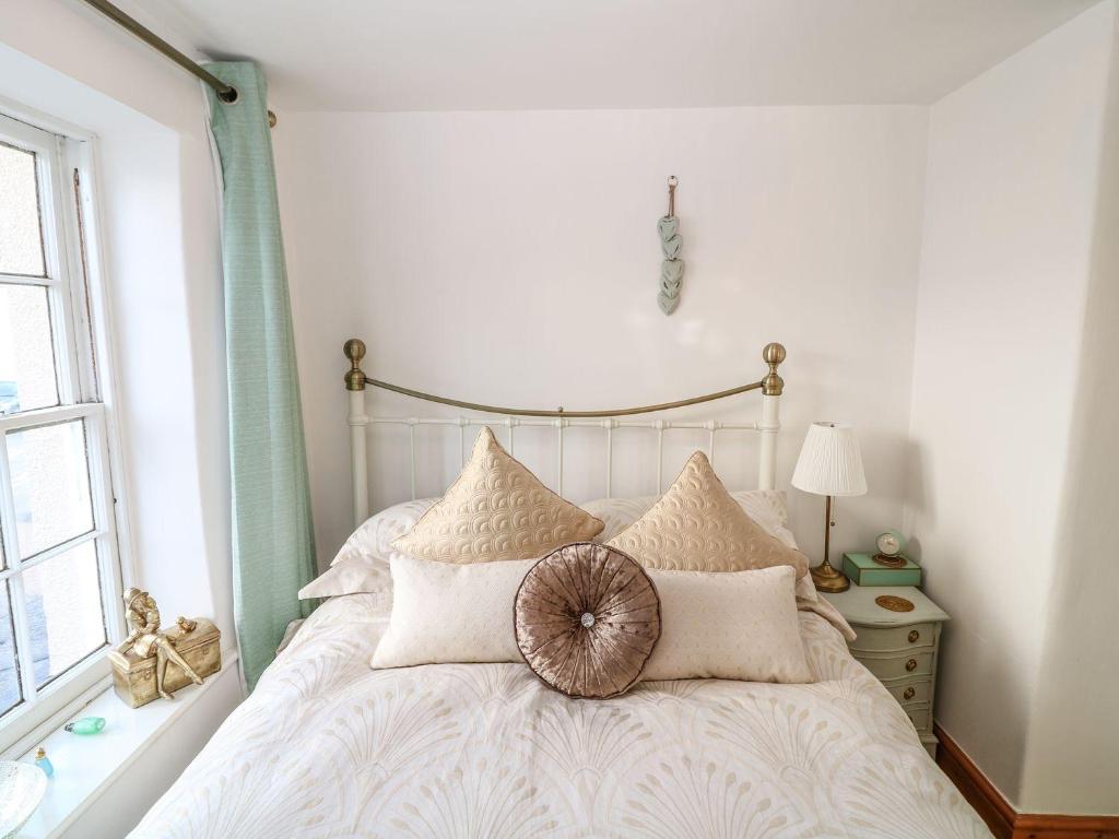 a bedroom with a white bed with pillows and a window at Higher Primrose Cottage in Winkleigh