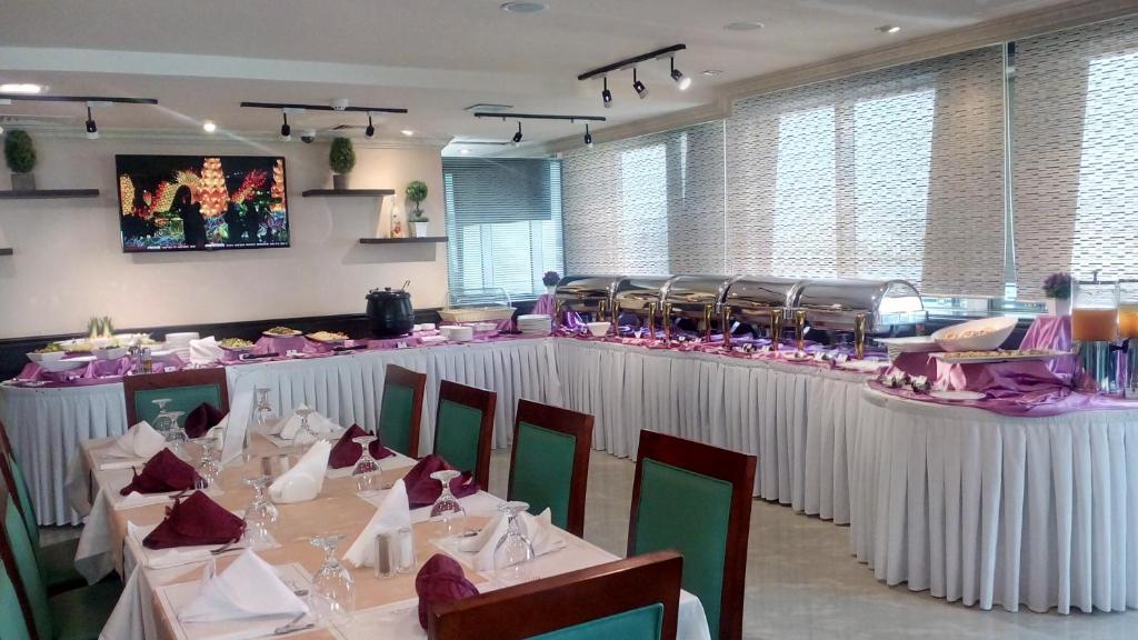 a dining room with white tables and chairs with pinkitures at Hala Inn Hotel Apartments - BAITHANS in Ajman 