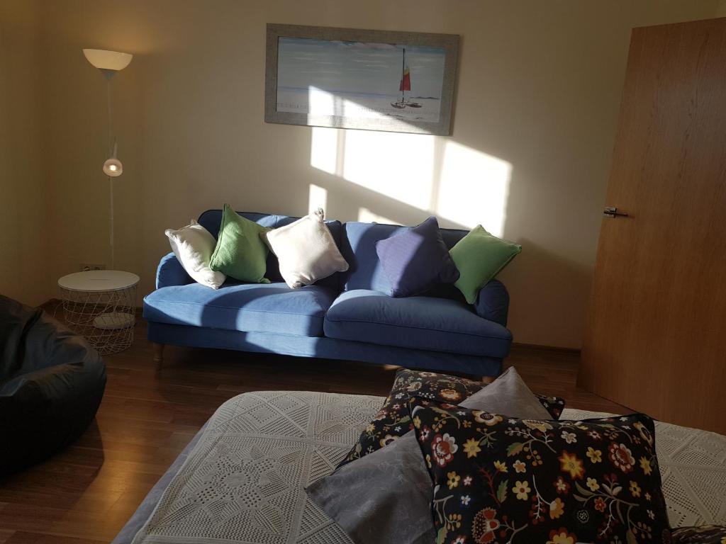 ein Wohnzimmer mit einem blauen Sofa und bunten Kissen in der Unterkunft Stylish apartment Riga in Riga