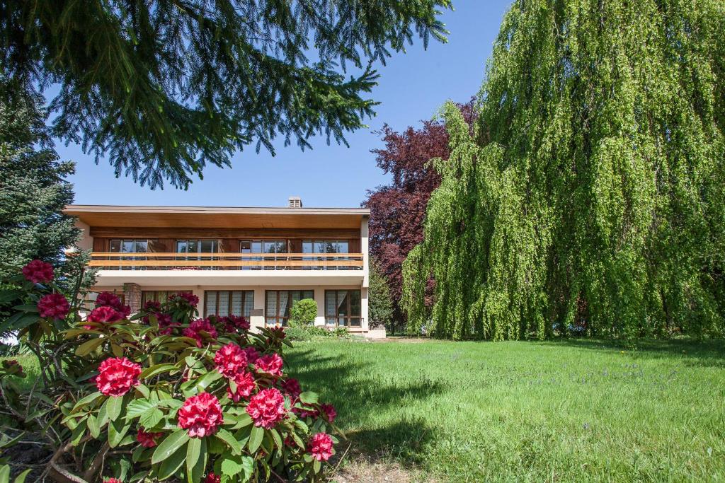 un bâtiment avec des fleurs roses dans une cour dans l'établissement Chambres d'hôtes Domaine des Iris, à Anould