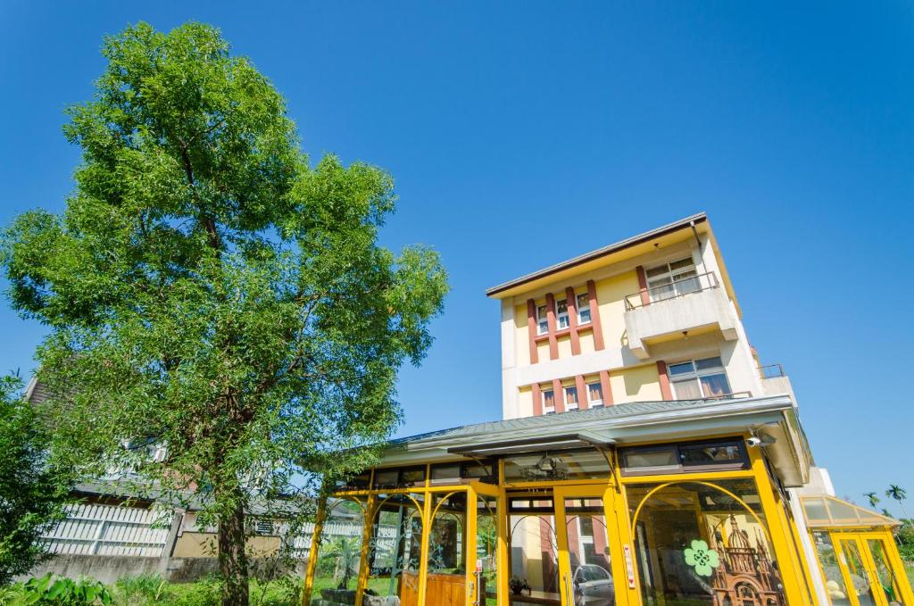 a building with a bus stop in front of a tree at 梅花湖-陽光屋民宿 in Dongshan