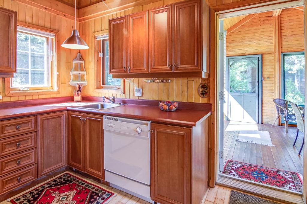 a kitchen with wooden cabinets and a white dishwasher at Le Cent in Saguenay