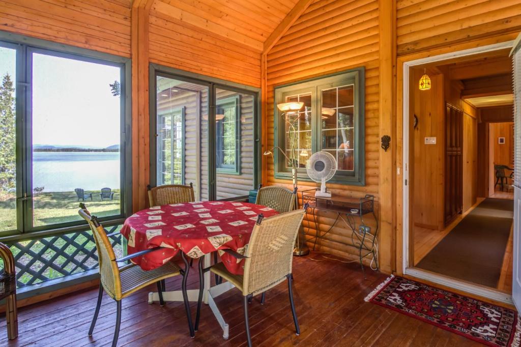 a dining room with a table and chairs and windows at Le Cent in Saguenay