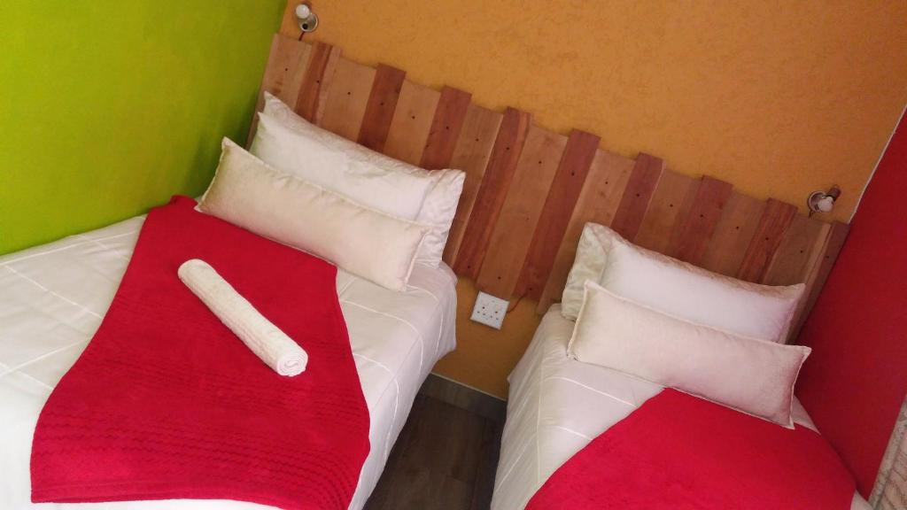 two beds with red and white pillows in a room at Mohalalitoe Bed and Breakfast in Maseru