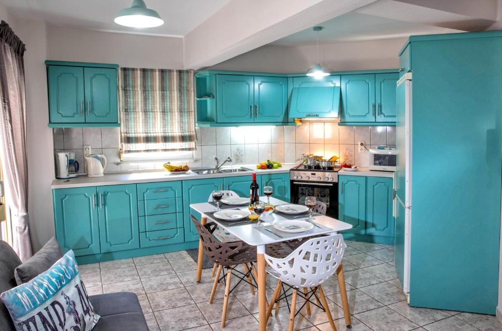 una cocina con armarios azules y una mesa con sillas en Holiday House Ioanna en Néa Péramos