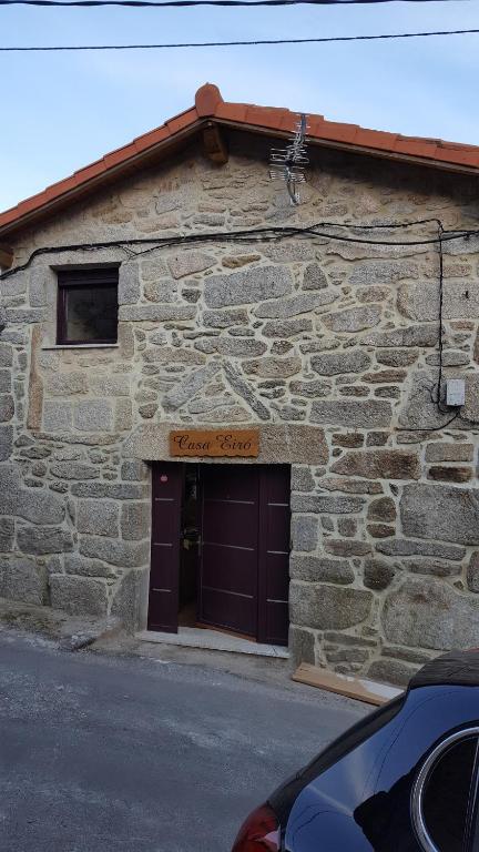 un edificio in pietra con una porta marrone del garage di CASA Eiró a Lobios