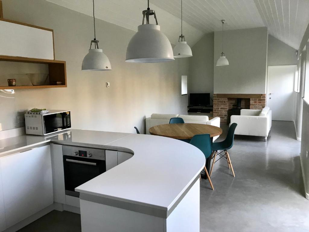 a kitchen with white counters and a table and chairs at Bury Knowle Stables in Oxford