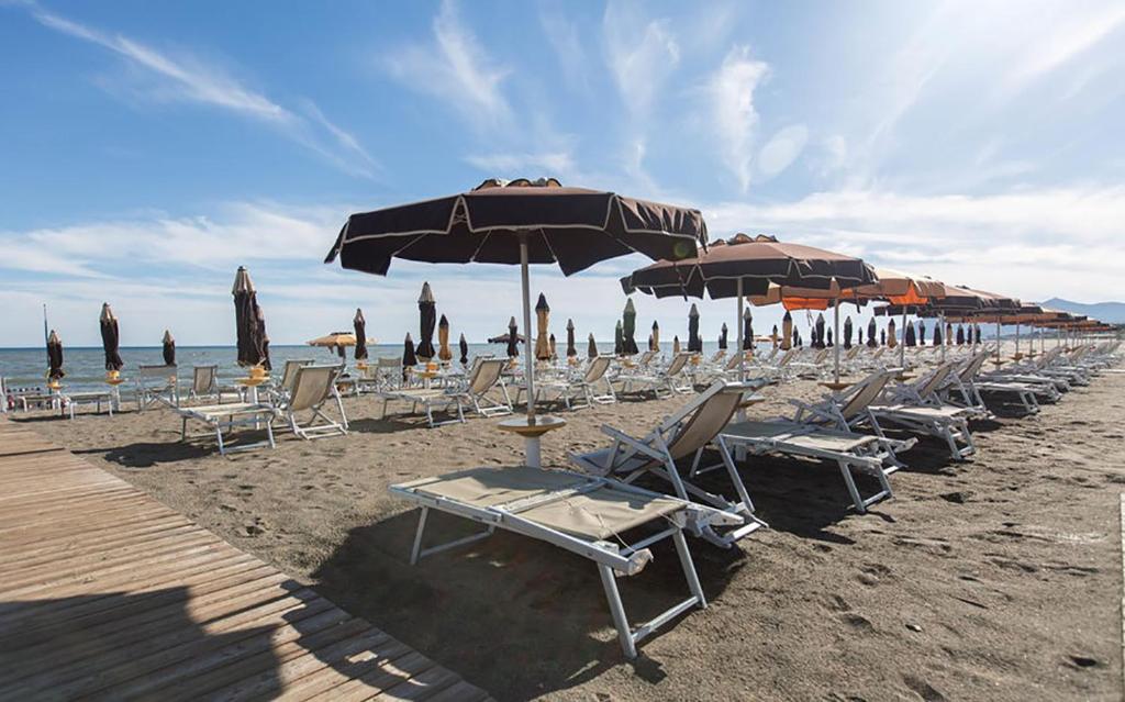 una fila de sillas y sombrillas en una playa en Hotel Anna, en Terracina