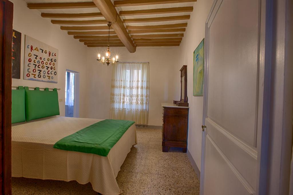 a bedroom with a bed with green sheets and a window at Ospiti del Borgo - Casa del Giusti in Lorenzana