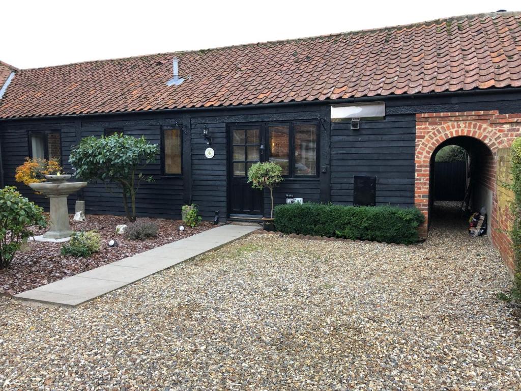 una casa nera con un sentiero davanti di Quince Cottage a Potter Heigham