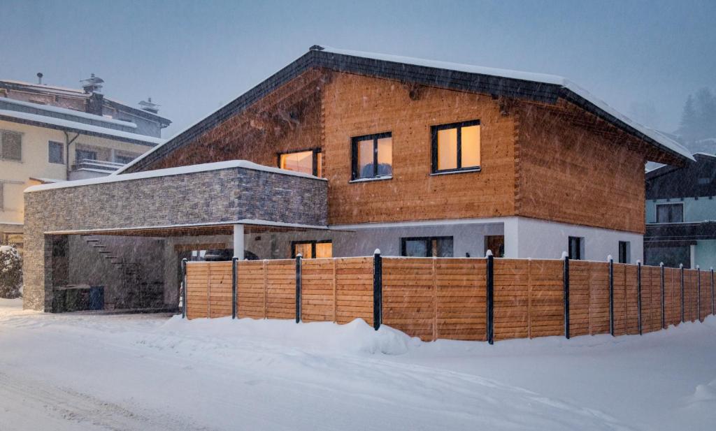 a brick house with a wooden fence in the snow at Appartment Sorgenfrei in Altenmarkt im Pongau