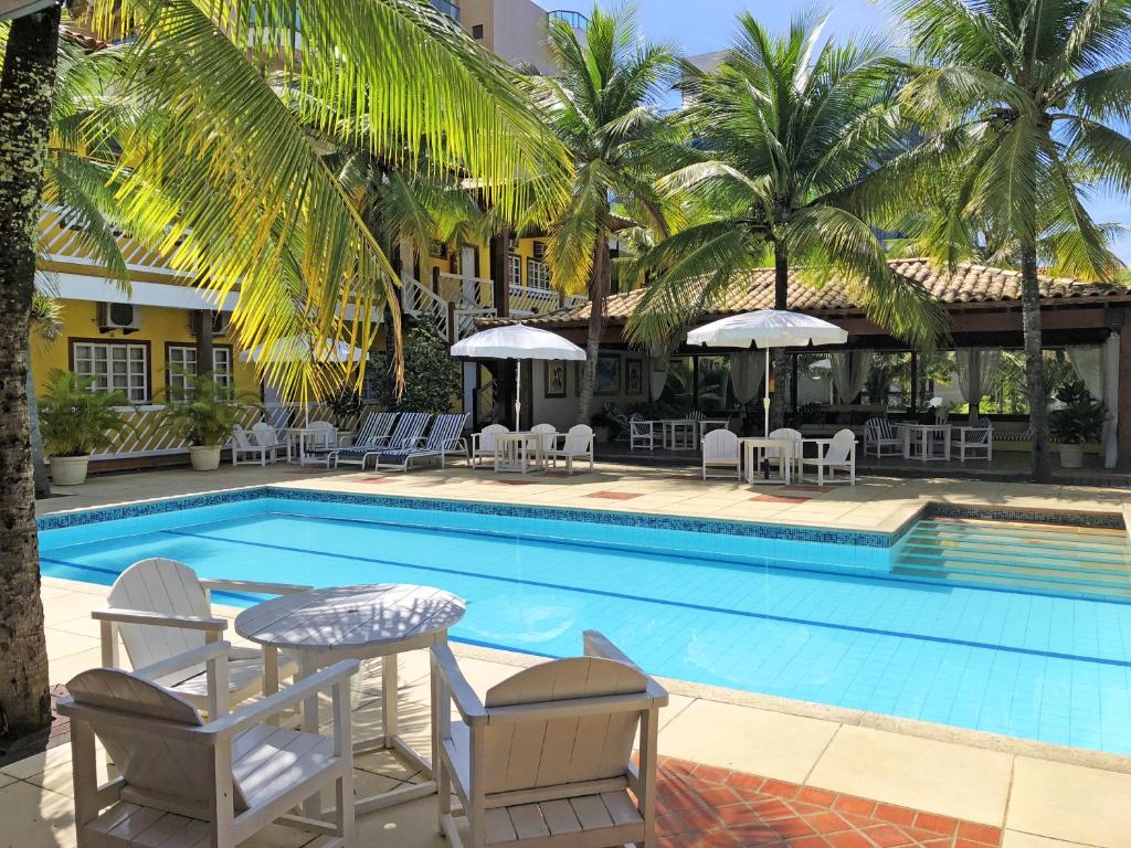 una piscina con sillas y sombrillas junto a un hotel en Hotel Mar de Cabo Frio, en Cabo Frío