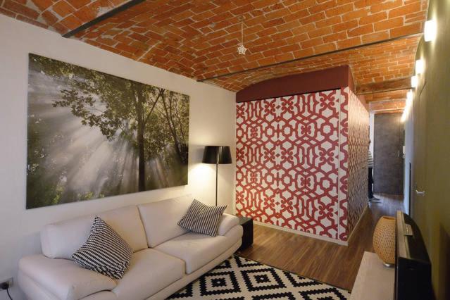 sala de estar con sofá blanco y pared de ladrillo en Appartamento in centro storico, en Asti