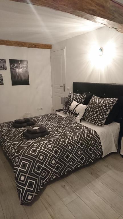 uma cama com um edredão preto e branco num quarto em Les Dauphins em Saint-Romain-de-Jalionas
