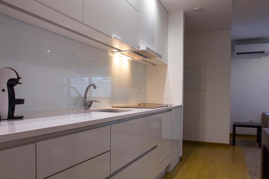 una cocina con armarios blancos y fregadero en Casa do Carvalho - Ponte de Lima, en Ponte de Lima