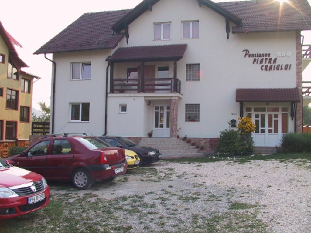 una casa con dos coches estacionados frente a ella en Pension Piatra Craiului, en Moieciu de Jos