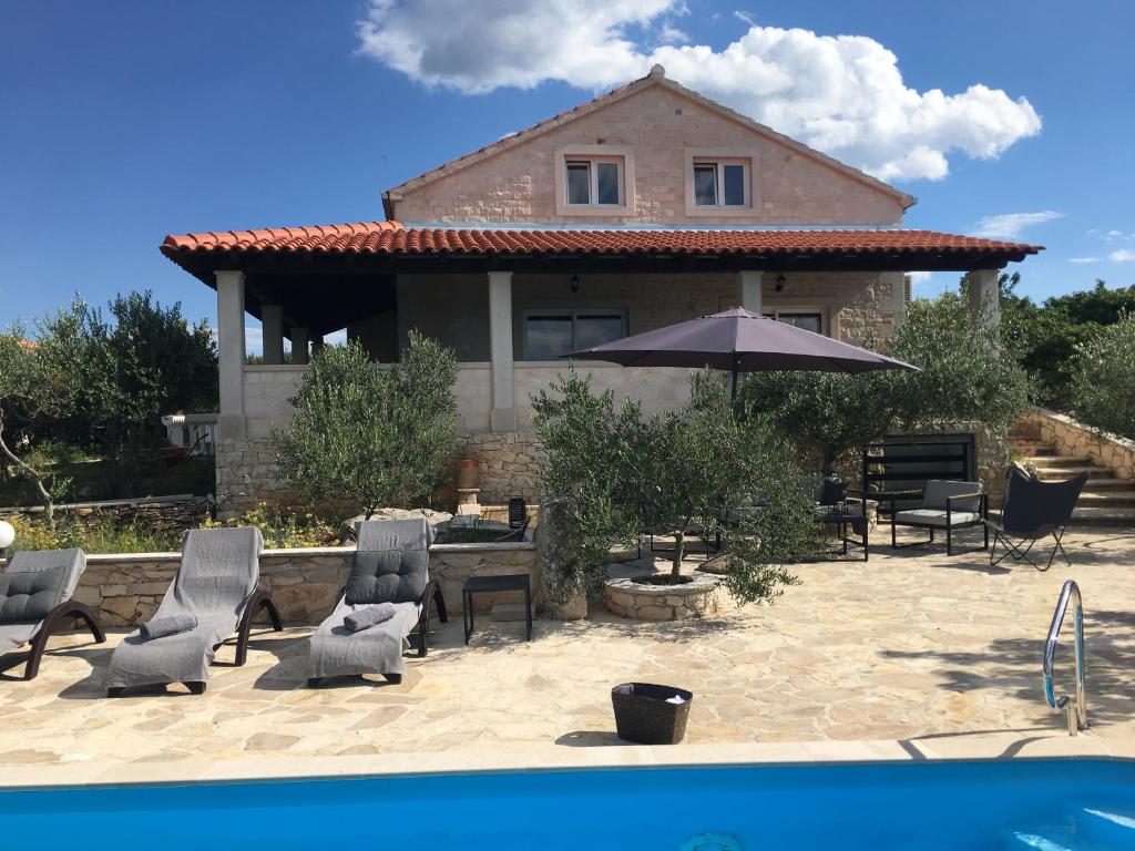 a house with a patio with chairs and an umbrella at Villa Belvedere Žiža in Donji Humac