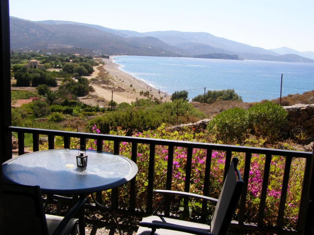 Ein Tisch und Stühle auf einem Balkon mit Blick auf einen Strand in der Unterkunft MARVINA in Volissos