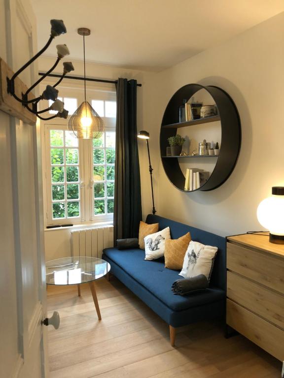 ein Wohnzimmer mit einem blauen Sofa und einem Spiegel in der Unterkunft Deauville centre, plage, casino et hippodrome in Deauville