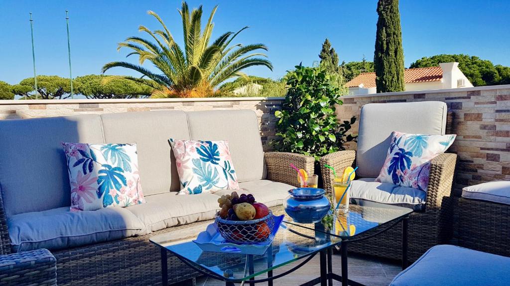 a patio with couches and a table with a bowl on it at Jardins do Golf, Val do Lobo in Almancil