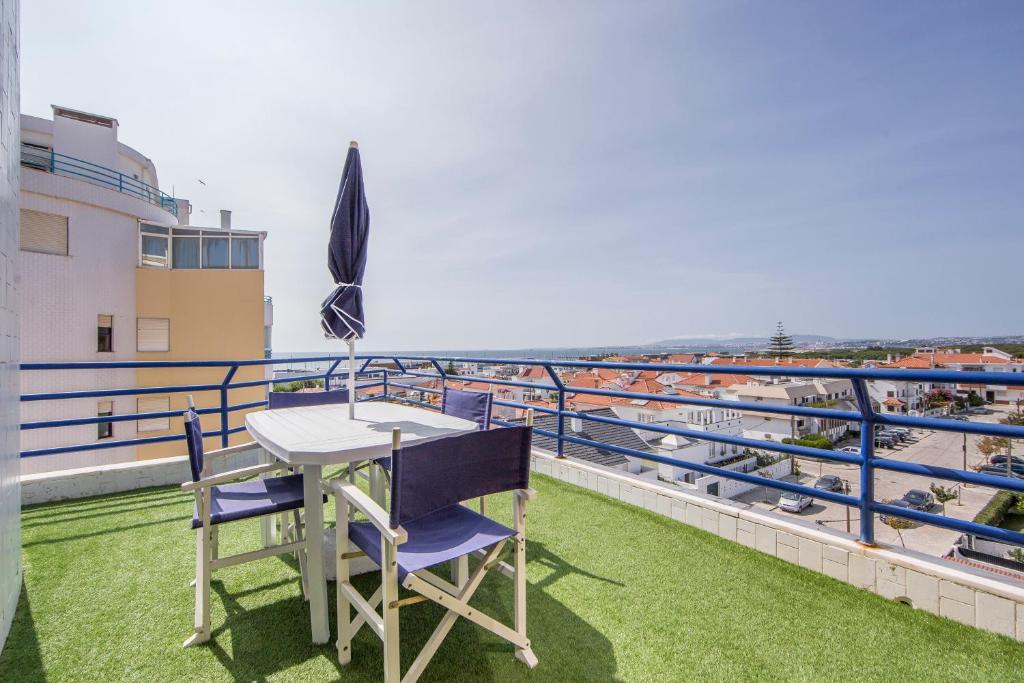 een tafel en stoelen op een balkon met uitzicht op de oceaan bij Av. 1º de Maio in Costa da Caparica