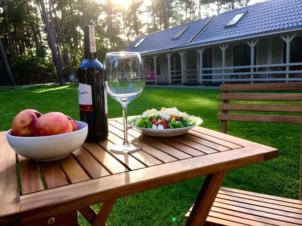 a picnic table with a glass of wine and a bowl of fruit at DIUNA Domki Letniskowe in Pobierowo