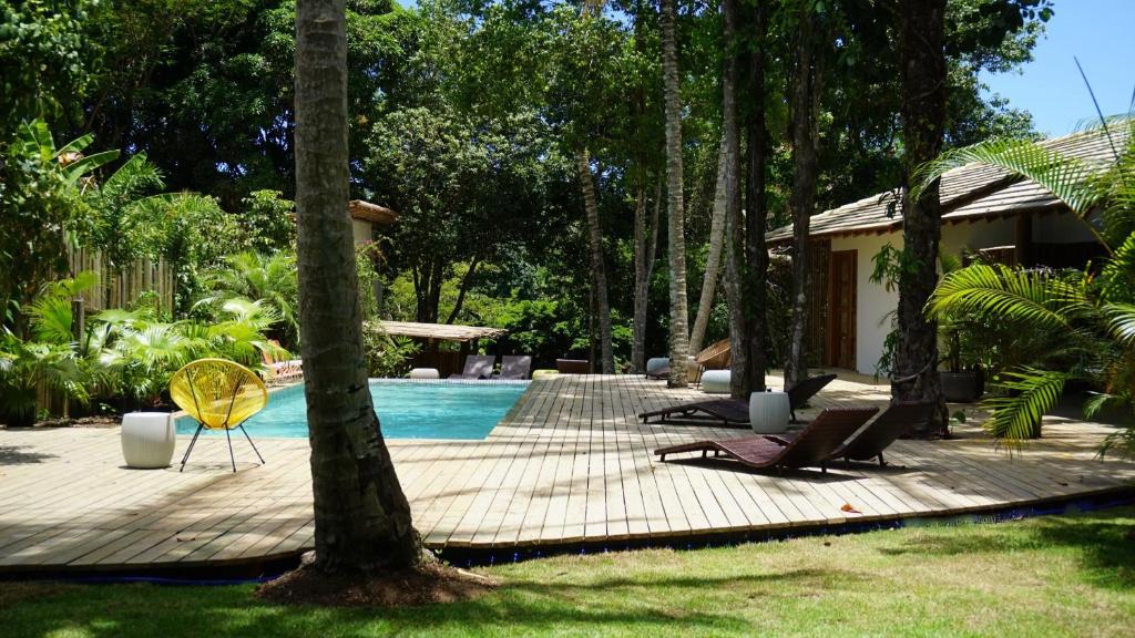 una piscina con una silla amarilla junto a una casa en Soleluna Casa Pousada, en Trancoso