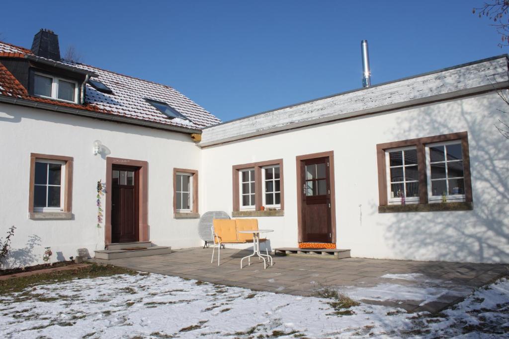 Casa blanca con una silla en el patio en Heinfried, en Auel