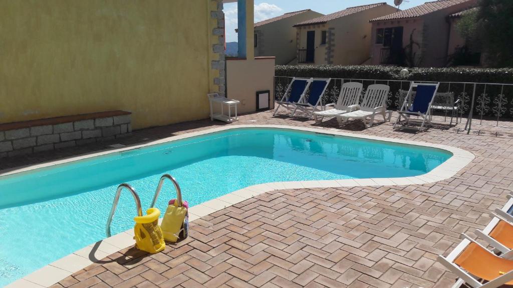 a swimming pool with chairs next to a house at Borgo Marino Badesi in Badesi
