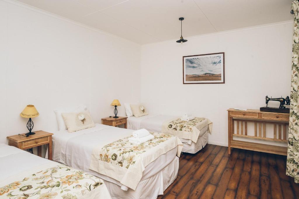 Habitación con 3 camas y 2 mesas con lámparas en Hotel Estancia El Ovejero Patagónico en Cerro Castillo