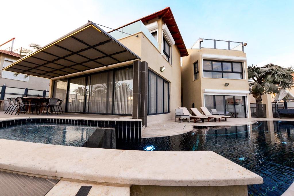 une maison avec une piscine en face d'une maison dans l'établissement Villa Daniela heated pool וילה דניאלה בריכה מחוממת, à Eilat