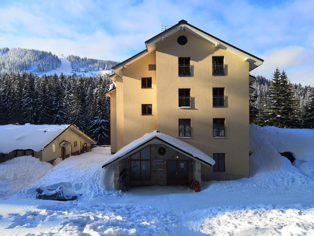 a large building is covered in snow with trees at Wellness Apartmán Pec in Pec pod Sněžkou