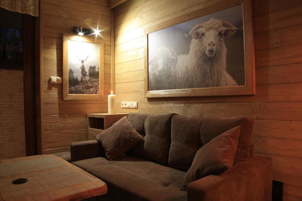 a living room with a couch and a picture of a sheep at Apartament Nad Potokiem in Szczawnica