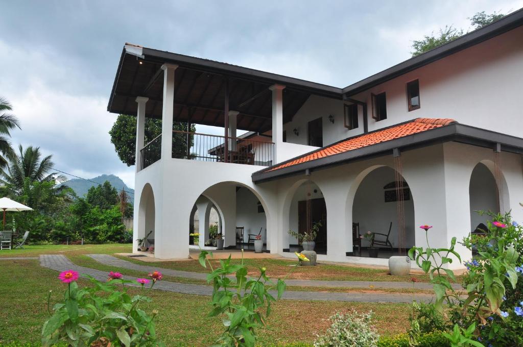 a white house with a balcony and a yard at Villa Nilmalee in Gampola