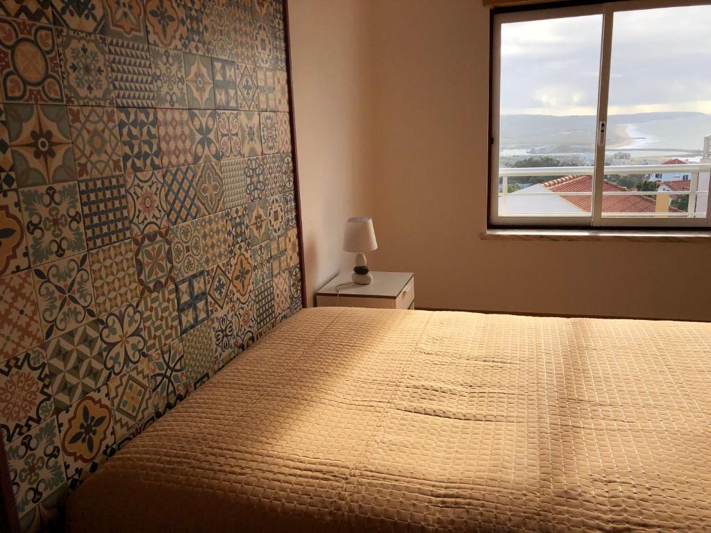 um quarto com uma cama grande e uma janela em Atlantic Nest Nazaré na Nazaré