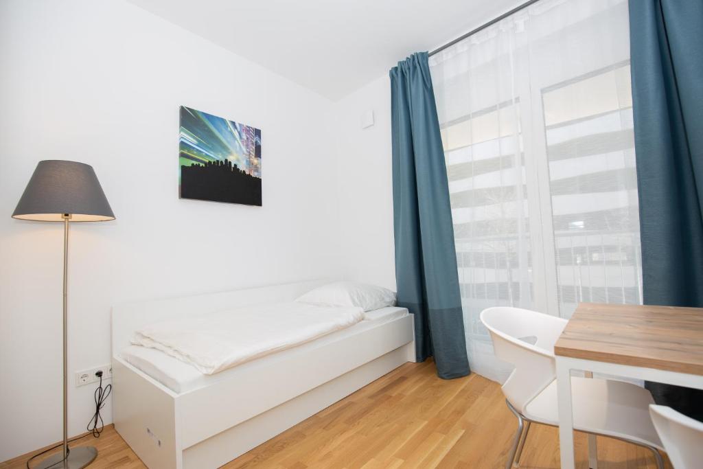 1 dormitorio con cama, escritorio y ventana en My room serviced apartment-Messe, en Múnich