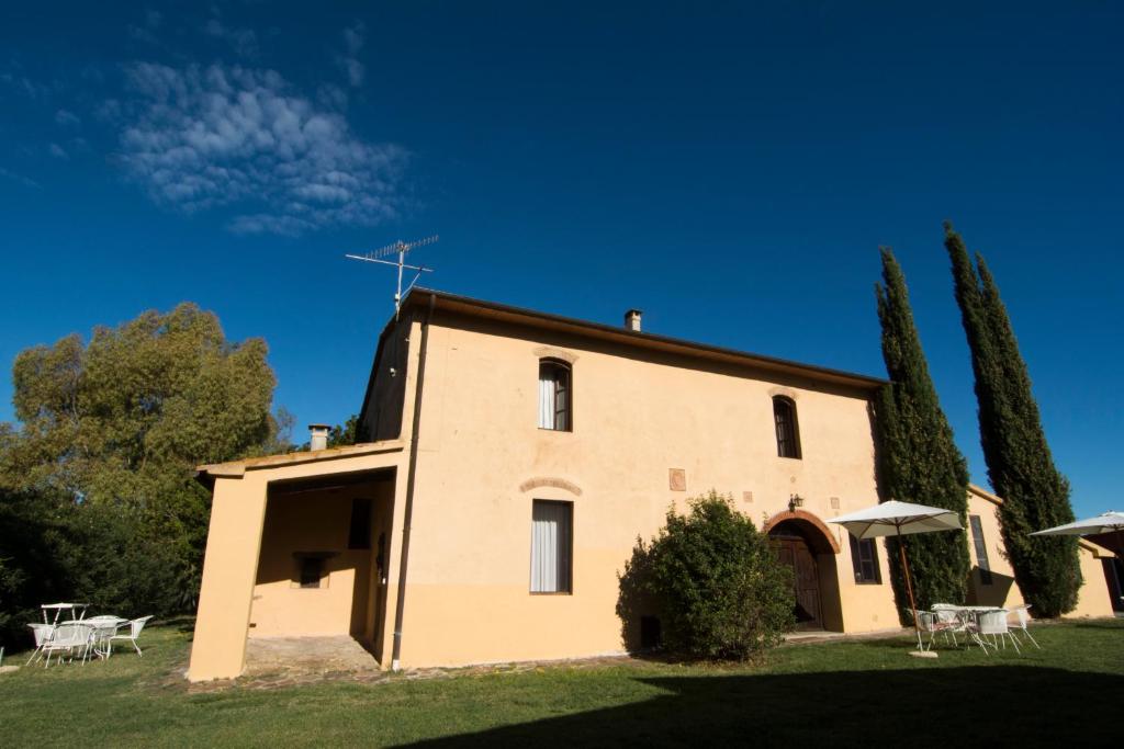 an old building with tables and chairs in a yard at Tenuta Col di Sasso in Scarlino