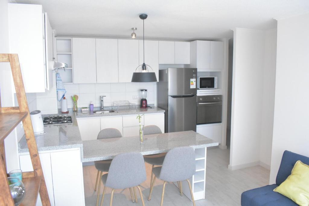 ラ・セレナにあるDepartamento avenida del marの白いキャビネットとテーブルと椅子のあるキッチン