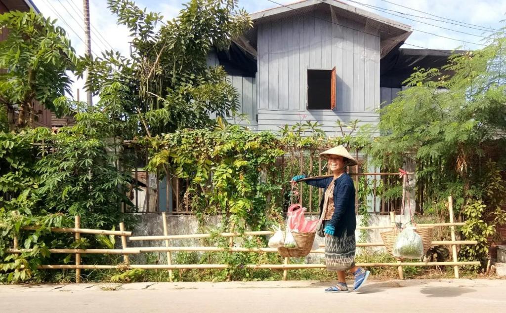 una mujer caminando por una calle con una cesta de pollos en Vanpila, en Savannakhet