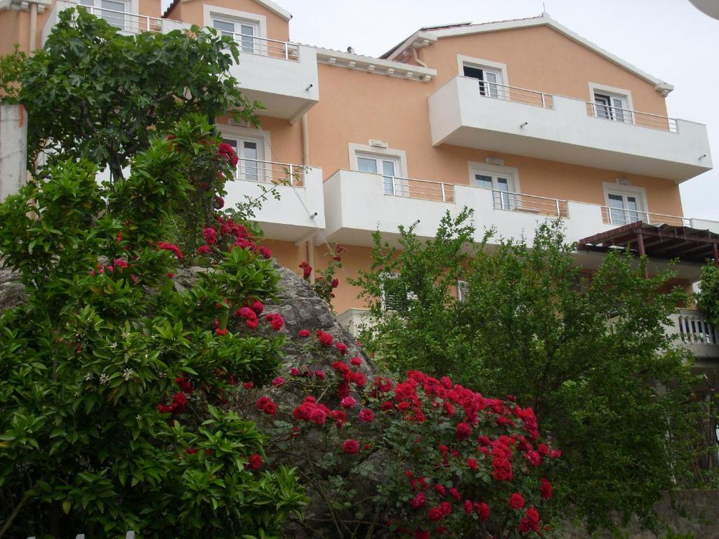 un bâtiment avec des fleurs roses devant lui dans l'établissement Apartments Bovan, à Herceg-Novi