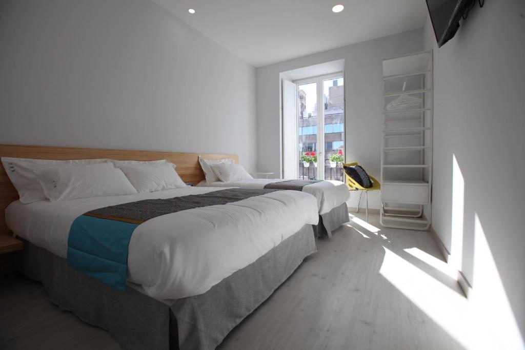 a bedroom with two beds and a window at Hostal Palacio Luna in Madrid