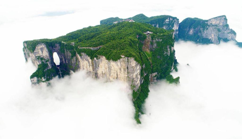 a mountain in the middle of a fog covered field at Home of heart Inn in Zhangjiajie